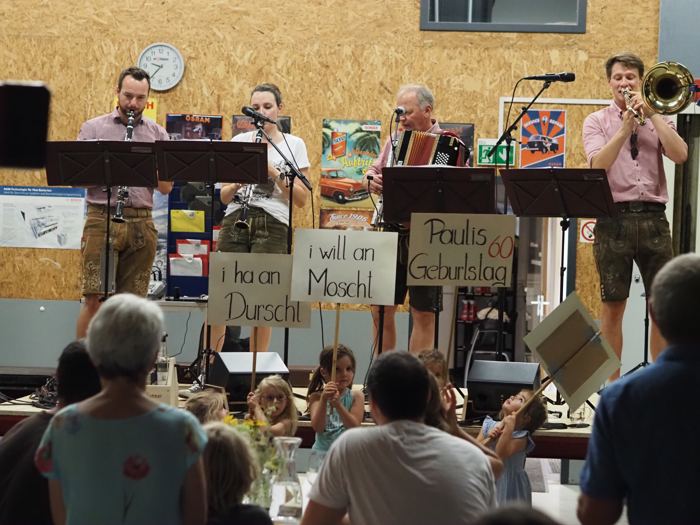 Die Hausmusik auf der Bühne, davor Kinder mit Schildern wie „i will koa Wasser“.