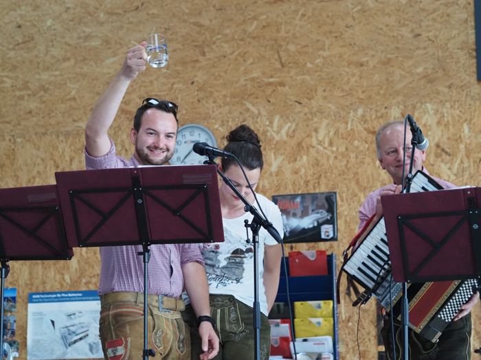 Ein Musiker hebt auf der Bühne sein Glas zum Prost.